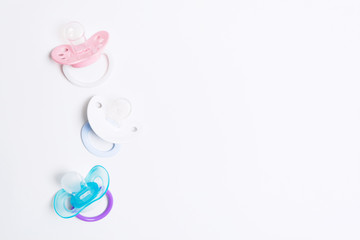 Three colorful baby silicone pacifier with holder on white background. Mock up. Flat lay. Orthodontic dummy for baby