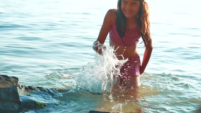 little girl bathes in the sea with rocks and stones. girl teen daughter swims in the water on the waves of the ocean. lifestyle summer vacation concept