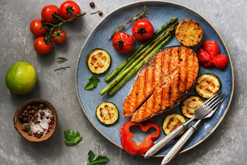 Grilled salmon with vegetables zucchini, asparagus, tomato, sweet pepper on a plate, gray...