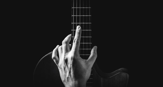 black and white male musician hand posing on guitar, isolated on black, music background 