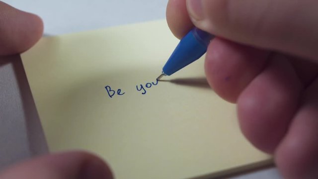 Motivation, inspiration, personal growth concept. Someone is writing BE YOURSELF on a sticker paper