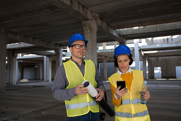 Female engineer looking at her smart phone on the construction site