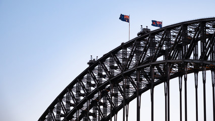 Closeup of the top of Sydney Harbour Bridge with waving Australian flags