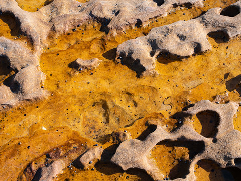 Orange and red rock formations on a beach in Royal National Park in Sydney