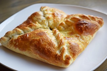 Khachapuri with vegetables and cheese on a white plate.