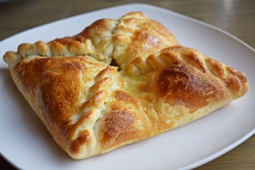 Khachapuri with vegetables and cheese on a white plate.