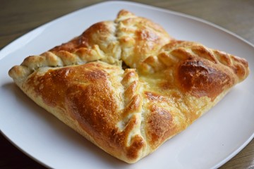 Khachapuri with vegetables and cheese on a white plate.