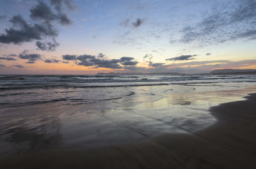 From the coast with wet sand, sea with waves, mountains there is a fantastic view of sunset sky that lights up with unbelievable colors. Nice warm autumn day. Location place Crete island, Greece.