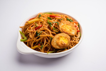 Egg Schezwan/hakka noodles, popular indochinese food served in a bowl with chopsticks. selective focus