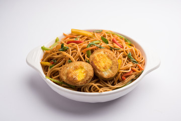 Egg Schezwan/hakka noodles, popular indochinese food served in a bowl with chopsticks. selective focus