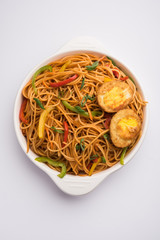 Egg Schezwan/hakka noodles, popular indochinese food served in a bowl with chopsticks. selective focus