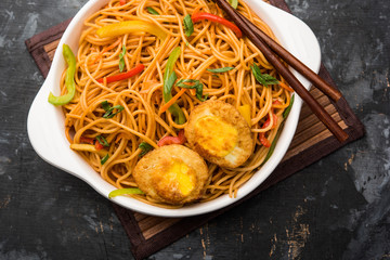 Egg Schezwan/hakka noodles, popular indochinese food served in a bowl with chopsticks. selective focus