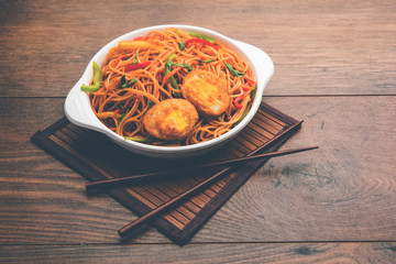 Egg Schezwan/hakka noodles, popular indochinese food served in a bowl with chopsticks. selective focus