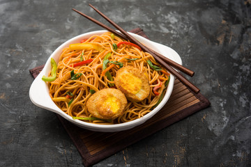 Egg Schezwan/hakka noodles, popular indochinese food served in a bowl with chopsticks. selective focus