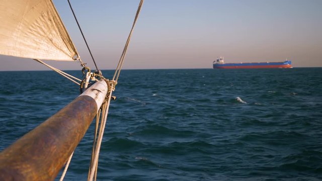Looking along bowsprit of sailing vessel at sea, towards distant oil tanker on the horizon