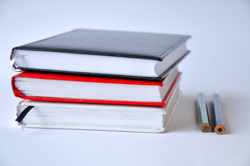 Several books or notebooks on a table on a white background