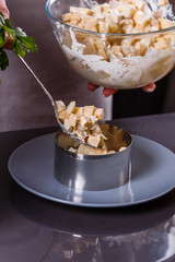 young woman in a gray aprons preparing Hawaiian salad
