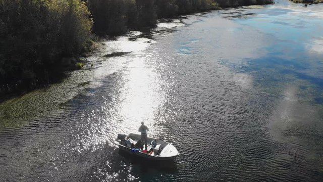 Aerial drone view of fisherman fly fishing from a drifting boat on a lake in New Zealand