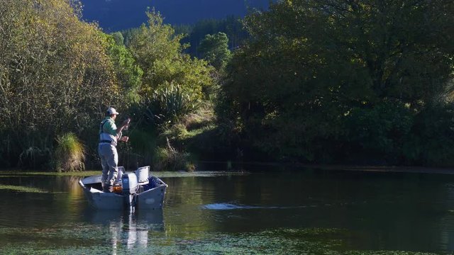 fly fisherman casting fly line from drifting boat to catch trout in new zealand