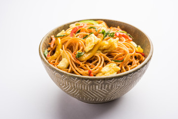 Egg Schezwan/hakka noodles, popular indochinese food served in a bowl with chopsticks. selective focus