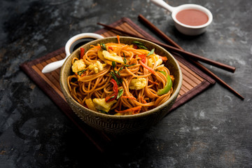 Egg Schezwan/hakka noodles, popular indochinese food served in a bowl with chopsticks. selective focus