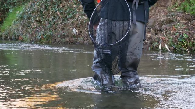 Fly fisherman walking in river and casting upstream slow motion