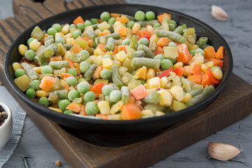 Frozen chopped vegetables in a boiling pan with spices. Vegan food.