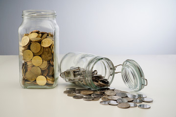 Gold coins spilling out of a jar  isolated on white background
