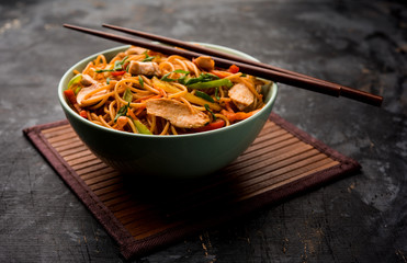 Chicken Hakka/Schezwan noodles served in a bowl with chopsticks. selective focus