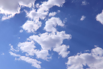 Blue sky background with white clouds on a sunny day. Nature concept. Horizontal, plenty of space for text.