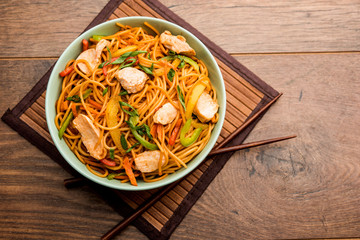 Chicken Hakka/Schezwan noodles served in a bowl with chopsticks. selective focus