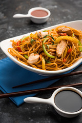 Chicken Hakka/Schezwan noodles served in a bowl with chopsticks. selective focus
