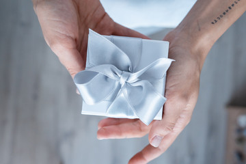 Woman hands holding Gift box with white bow, close-up