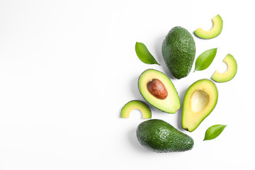 Flat lay composition with ripe avocados and leaves on white background, space for text
