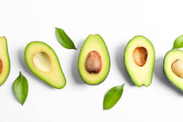 Flat lay composition with ripe avocados and leaves on white background, top view