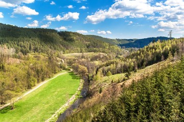 Valley with the river in the Czech Republic. Spring day in nature. View of the valley on the river. Wooded hills.