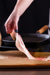 young woman in a gray apron fries bacon