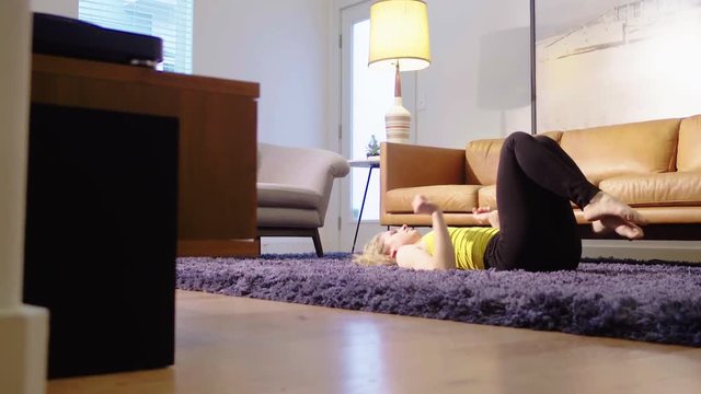 Attractive blonde woman working out, moving from backbend pose to touch toes stretch. Low angle shot 4k