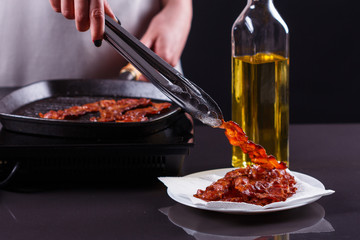 young woman in a gray apron fries bacon