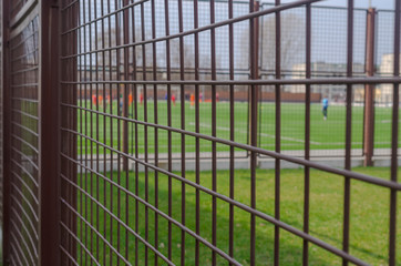 Football field through the iron bars of the fence.