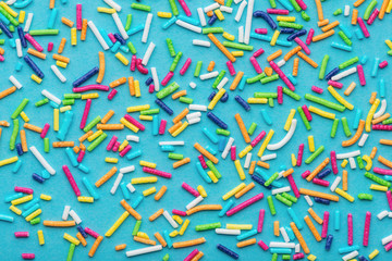 pattern of colorful sprinkles over blue background, festive decoration for cake and bakery