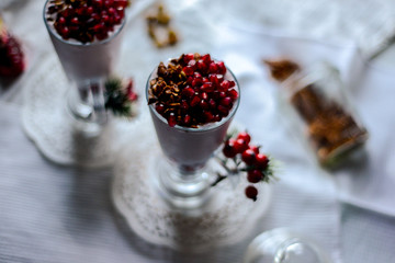 tasty breakfast  from creamy pomegranate dessert with homemade granola in hight glasses decorated with red berries on the ight background in the winter morning