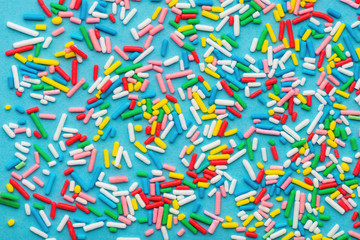 Fototapeta na wymiar top view of colorful sprinkles over blue background, festive decoration for Valentines day, birthday, holiday and party time