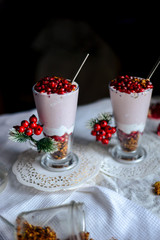 tasty breakfast  from creamy pomegranate dessert with homemade granola in hight glasses decorated with red berries on the ight background in the winter morning