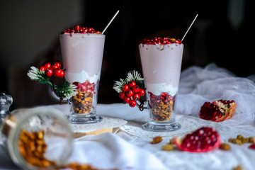 tasty breakfast  from creamy pomegranate dessert with homemade granola in hight glasses decorated with red berries on the ight background in the winter morning