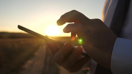 the hands of a man are driving their fingers over the tablet. close-up. man checks email. Businessman working on tablet at sunset.