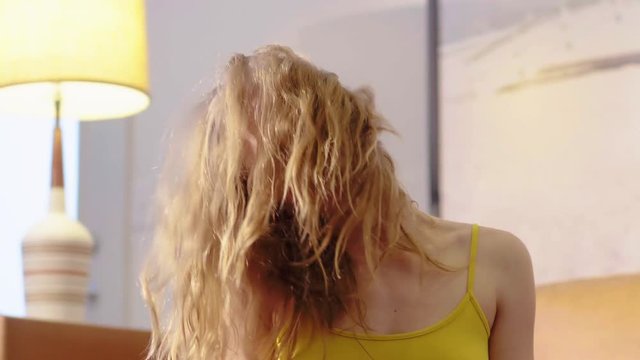 Long blonde hair covering a beautiful woman's face as she stretches her neck during a home yoga and stretching workout. Close up.