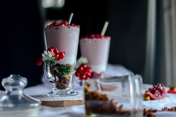 tasty breakfast  from creamy pomegranate dessert with homemade granola in hight glasses decorated with red berries on the ight background in the winter morning