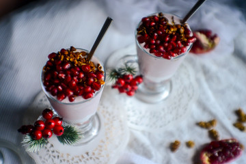 tasty breakfast  from creamy pomegranate dessert with homemade granola in hight glasses decorated with red berries on the ight background in the winter morning