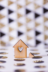 Obraz na płótnie Canvas Closeup wooden house with hole in form of heart on geometric abstract background with golden glitter.
